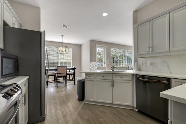 kitchen featuring pendant lighting, sink, decorative backsplash, hardwood / wood-style flooring, and stainless steel appliances