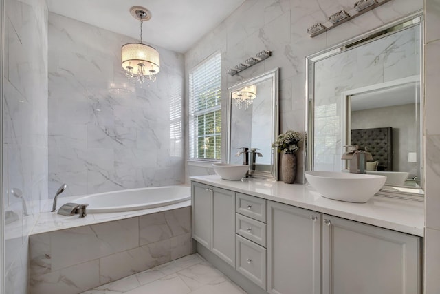 bathroom featuring vanity, a relaxing tiled tub, and an inviting chandelier