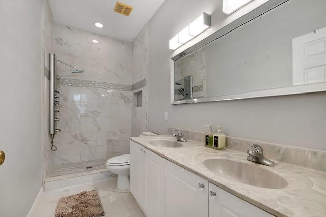 bathroom with vanity, tiled shower, and toilet