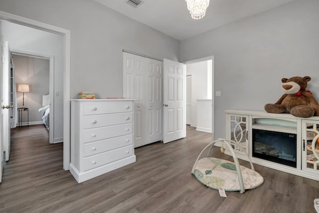 bedroom with dark wood-type flooring, a chandelier, and a closet