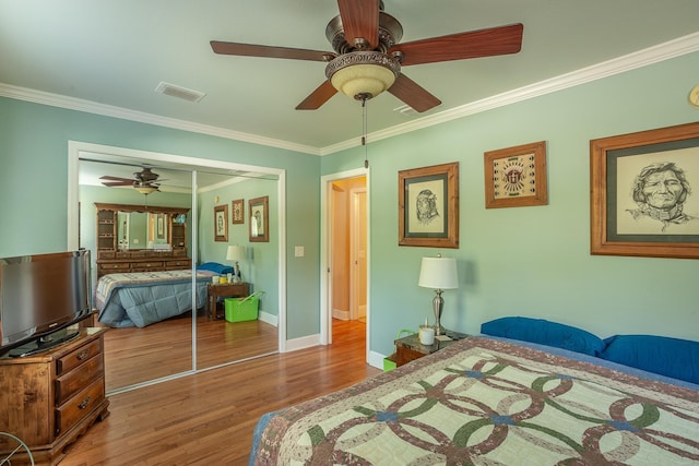 bedroom with hardwood / wood-style floors, ceiling fan, ornamental molding, and a closet