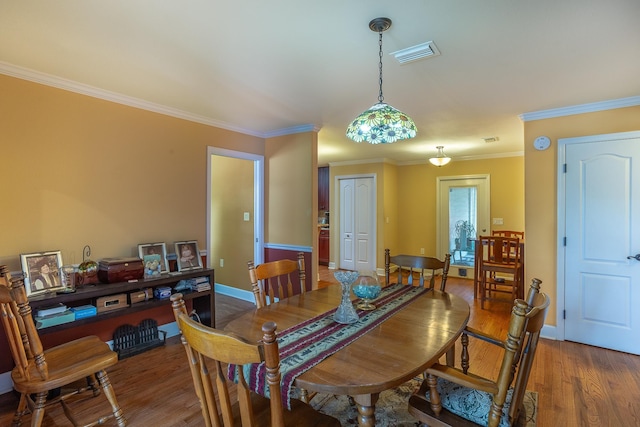 dining area with wood-type flooring and crown molding