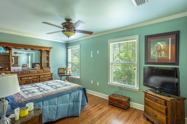 bedroom with multiple windows, wood-type flooring, ceiling fan, and crown molding