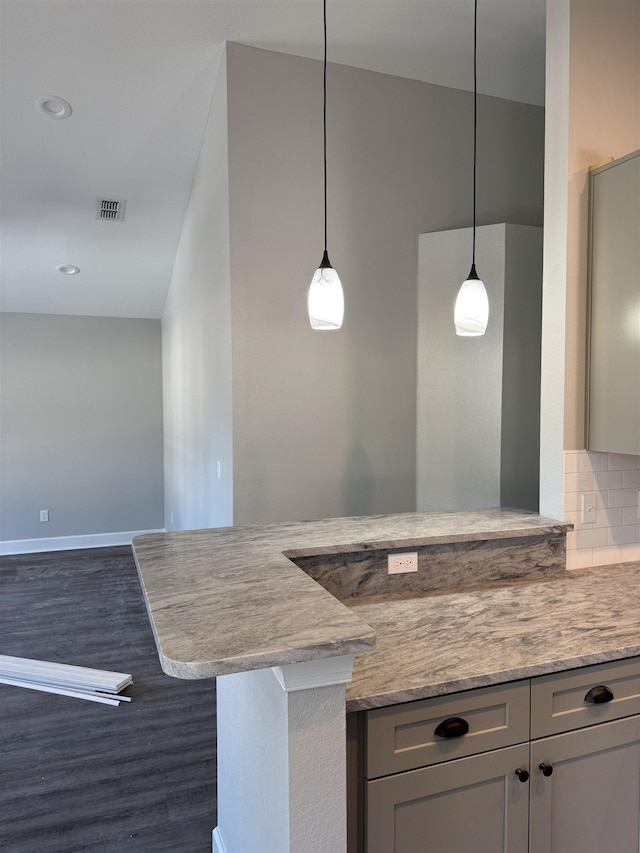 kitchen with kitchen peninsula, a breakfast bar area, backsplash, dark wood-type flooring, and pendant lighting