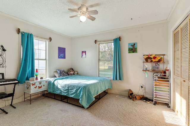 bedroom with ceiling fan, ornamental molding, carpet, a textured ceiling, and a closet