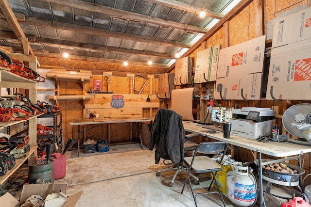 misc room with lofted ceiling, unfinished concrete flooring, wooden walls, and a workshop area