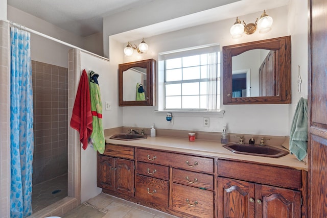 full bathroom with double vanity, tiled shower, a sink, and tile patterned floors