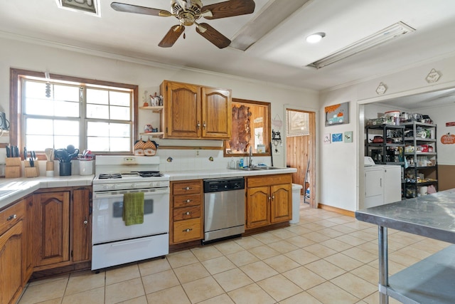 kitchen with dishwasher, brown cabinets, a sink, separate washer and dryer, and gas range gas stove