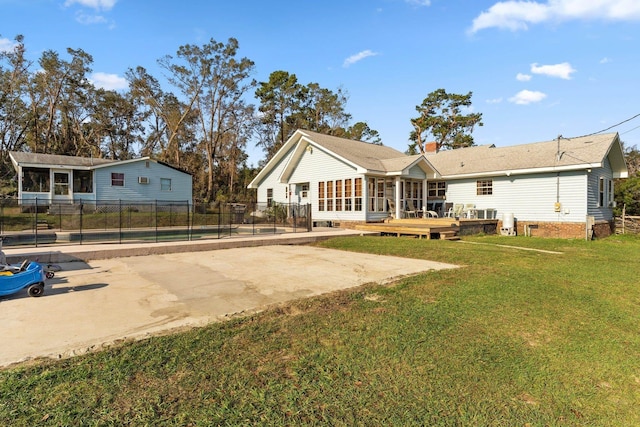 back of property featuring driveway, a lawn, a sunroom, fence, and a patio area