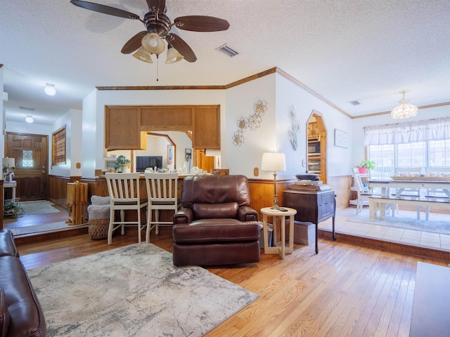 181 NE Biltmore Rd, Madison, FL 32340 - living area featuring light wood-style flooring, ceiling fan, a wainscoted wall, a textured ceiling, and ornamental molding