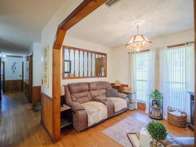 181 NE Biltmore Rd, Madison, FL 32340 - living room with a textured ceiling, a chandelier, wood finished floors, a wainscoted wall, and wooden walls