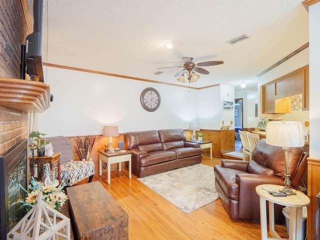 181 NE Biltmore Rd, Madison, FL 32340 - living area with a textured ceiling, a ceiling fan, light wood-style floors, a fireplace, and ornamental molding