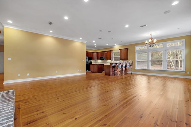 living room featuring ornamental molding, a chandelier, and light hardwood / wood-style flooring