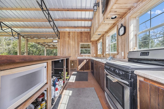 interior space with light countertops, white microwave, stainless steel range with electric cooktop, a sink, and wooden walls