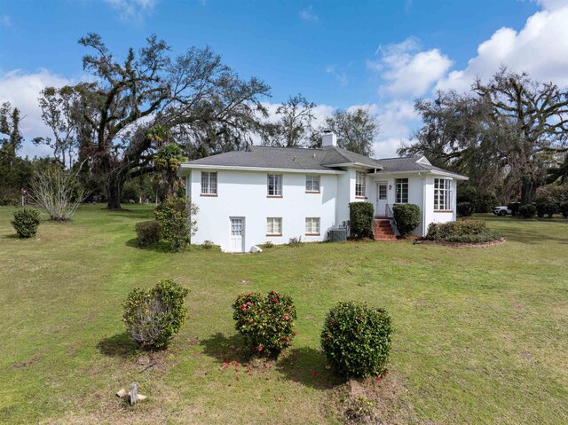 view of front of property with a front lawn, a chimney, and stucco siding