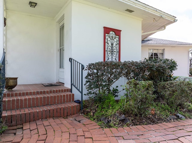 property entrance featuring visible vents and stucco siding