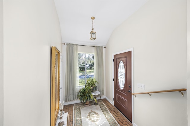 foyer entrance featuring vaulted ceiling, brick floor, and baseboards