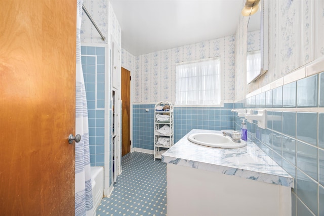 bathroom featuring a wainscoted wall, shower / bath combination, tile walls, vanity, and wallpapered walls