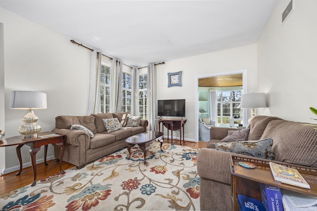 living room featuring wood finished floors, visible vents, and baseboards