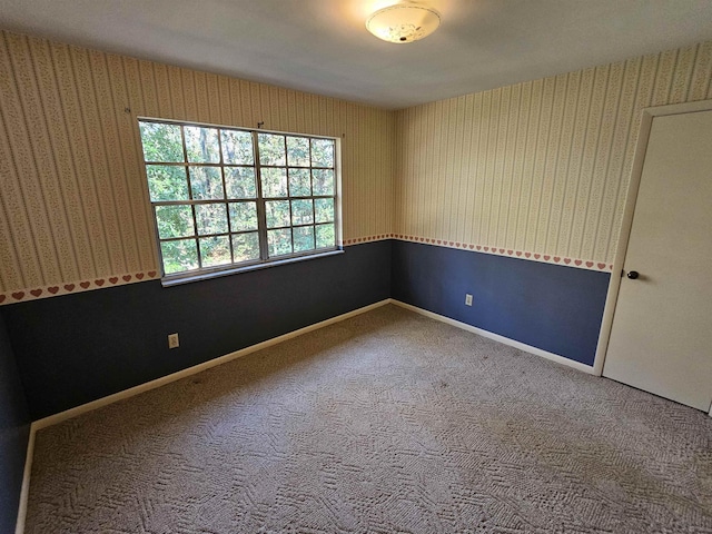 spare room with wallpapered walls, carpet, and baseboards