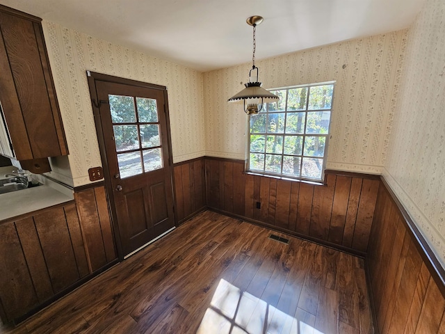 unfurnished dining area featuring dark wood finished floors, visible vents, wainscoting, a sink, and wallpapered walls