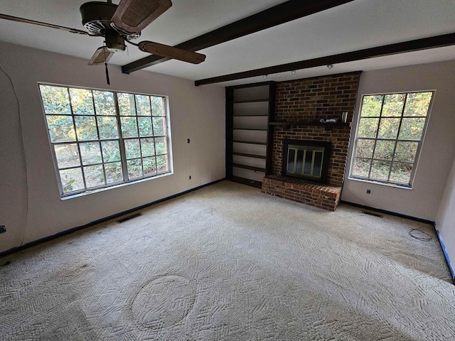 unfurnished living room featuring light carpet, a wealth of natural light, visible vents, and beamed ceiling