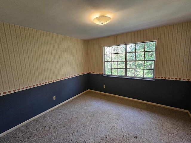 spare room with wallpapered walls, baseboards, and carpet flooring