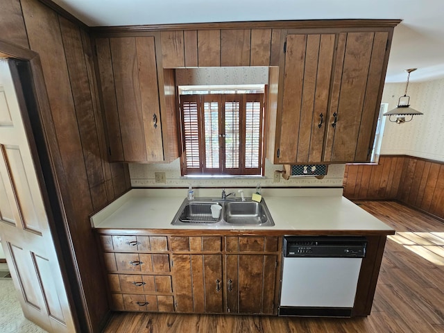 kitchen featuring light countertops, hanging light fixtures, dark wood-type flooring, white dishwasher, and a sink