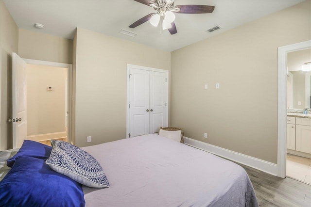 bedroom with visible vents, a ceiling fan, ensuite bath, wood finished floors, and baseboards