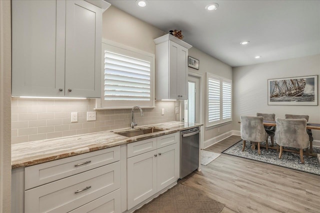 kitchen with tasteful backsplash, dishwasher, light wood-style floors, white cabinetry, and a sink