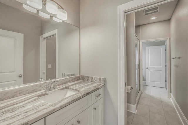 full bathroom featuring vanity, tile patterned floors, visible vents, and a shower with door