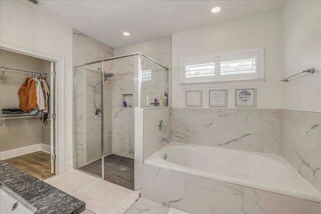 full bath featuring a marble finish shower, recessed lighting, a spacious closet, and a garden tub