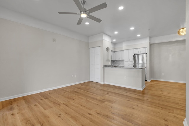 unfurnished living room featuring ceiling fan and light wood-type flooring