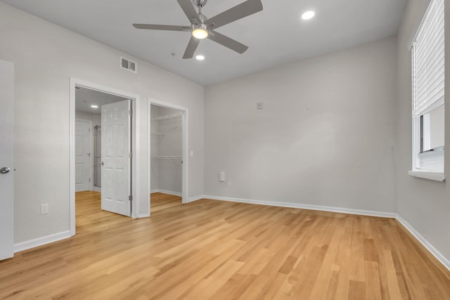 unfurnished bedroom featuring ceiling fan, a closet, a spacious closet, and light hardwood / wood-style flooring