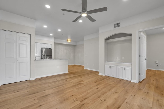 unfurnished living room with light wood-type flooring, ceiling fan, and sink