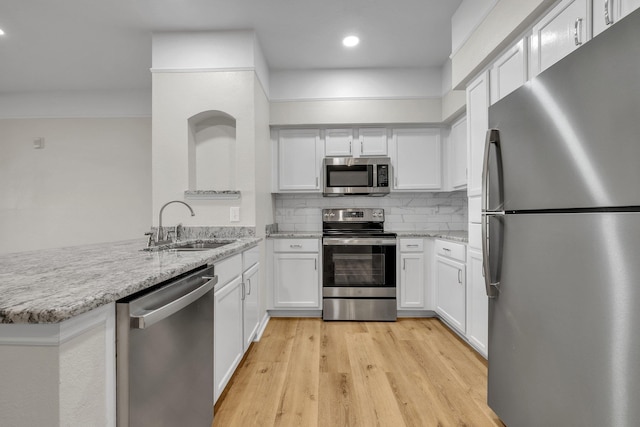 kitchen featuring kitchen peninsula, appliances with stainless steel finishes, white cabinetry, and sink