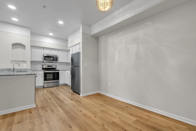 kitchen featuring white cabinetry, light hardwood / wood-style flooring, light stone counters, and appliances with stainless steel finishes