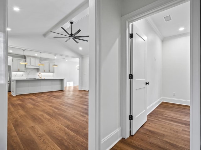 hallway with dark wood-type flooring, sink, and vaulted ceiling with beams