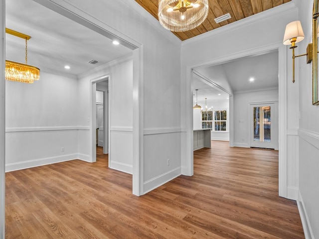 spare room with crown molding, wood-type flooring, an inviting chandelier, and wooden ceiling