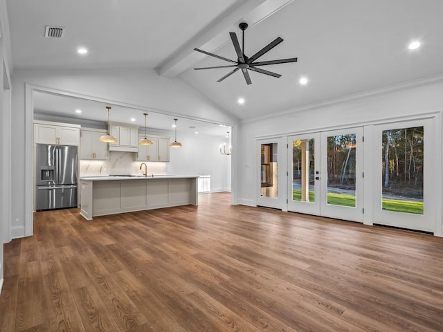 unfurnished living room featuring vaulted ceiling with beams, sink, ceiling fan with notable chandelier, and hardwood / wood-style flooring