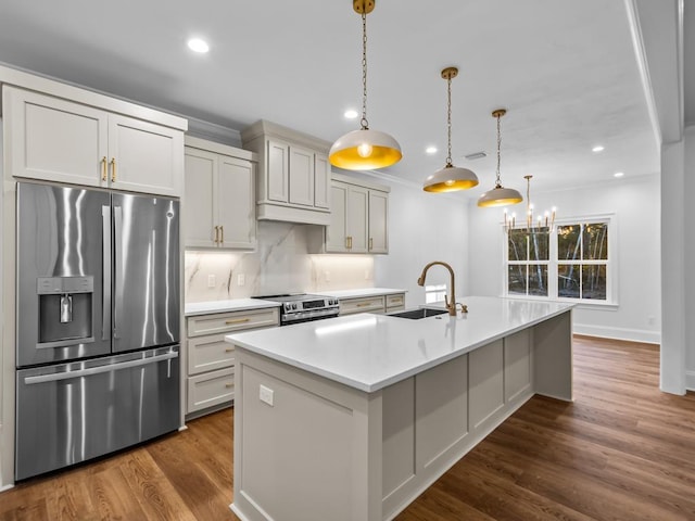 kitchen featuring an island with sink, appliances with stainless steel finishes, dark hardwood / wood-style flooring, pendant lighting, and sink