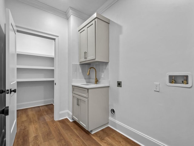 washroom with dark hardwood / wood-style floors, sink, hookup for a washing machine, ornamental molding, and hookup for an electric dryer