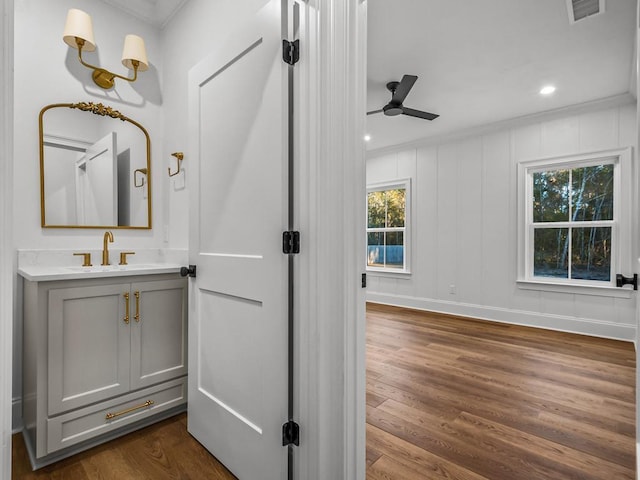 bathroom with ceiling fan, crown molding, hardwood / wood-style flooring, and vanity