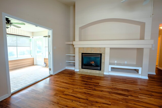 9321 Royal Troon Dr, Tallahassee, FL 32312 - unfurnished living room featuring ceiling fan, wood finished floors, a tiled fireplace, built in features, and baseboards