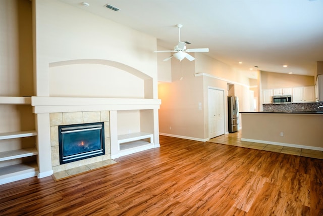 9321 Royal Troon Dr, Tallahassee, FL 32312 - unfurnished living room with a ceiling fan, a tiled fireplace, light wood-type flooring, recessed lighting, and baseboards