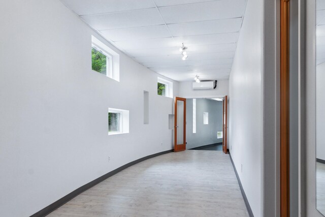 hallway featuring light wood-type flooring and a wall mounted air conditioner