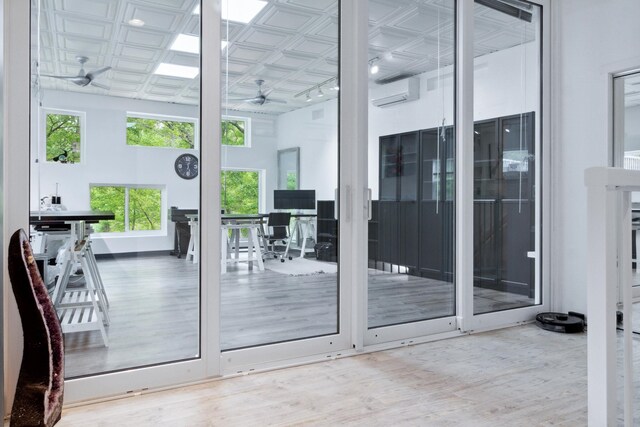 doorway with hardwood / wood-style flooring, an AC wall unit, ceiling fan, and a high ceiling