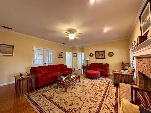 living area featuring visible vents, wood finished floors, crown molding, and a brick fireplace