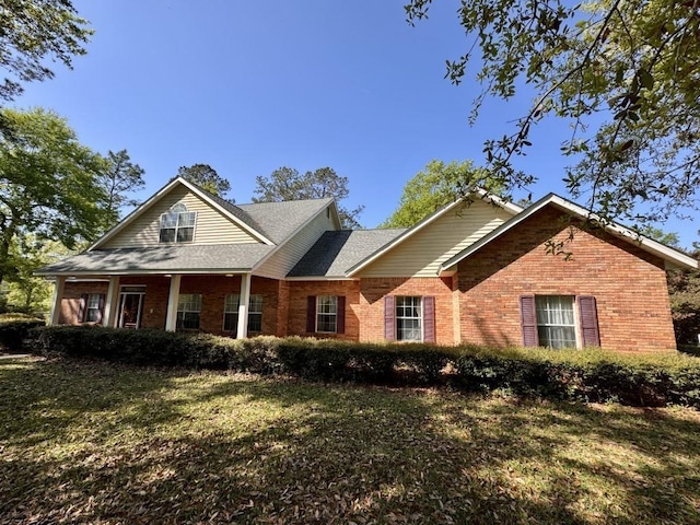 view of front of house with a front lawn, a shingled roof, and brick siding