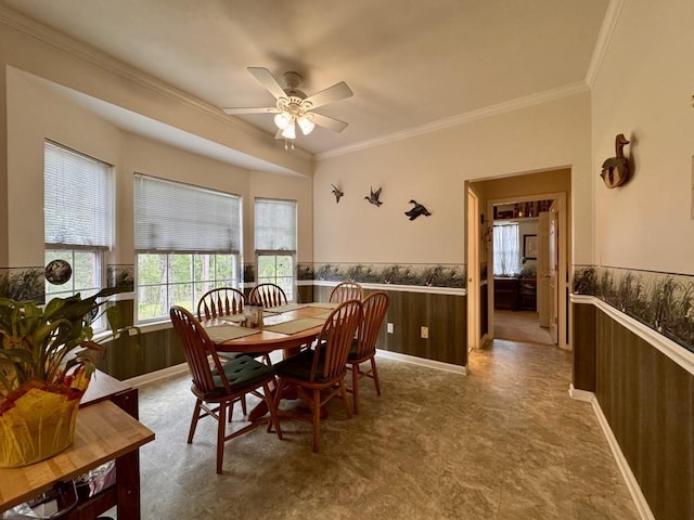 dining room featuring crown molding, a wainscoted wall, ceiling fan, and tile patterned floors